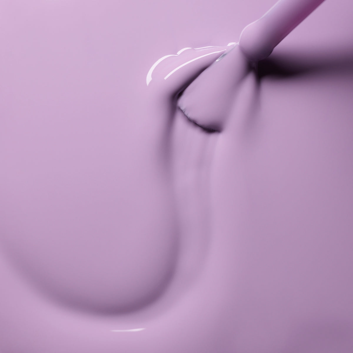 Gros plan sur le pinceau Lisa Lilas de Manucurist appliquant avec fluidité un vernis gel lilas brillant, révélant une texture onctueuse et laquée aux reflets doux et aux accents subtilement 90s.