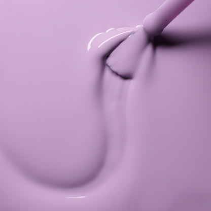 Gros plan sur le pinceau Lisa Lilas de Manucurist appliquant avec fluidité un vernis gel lilas brillant, révélant une texture onctueuse et laquée aux reflets doux et aux accents subtilement 90s.