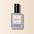 Un flacon de vernis à ongles Manucurist Lilas avec un bouchon noir et l’étiquette « Nail Polish Lilas, Quick Dry, Intense Color » est posé sur un fond beige clair à côté d’un vernis bleu pastel.