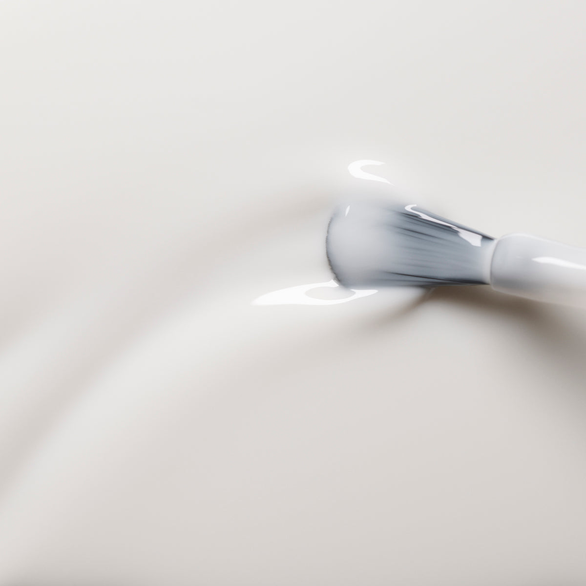 Gros plan sur un pinceau doux étalant le vernis Green™ Milky White de Manucurist — une formule blanc crème onctueuse — sur une surface, créant de légères ondulations et des reflets brillants.