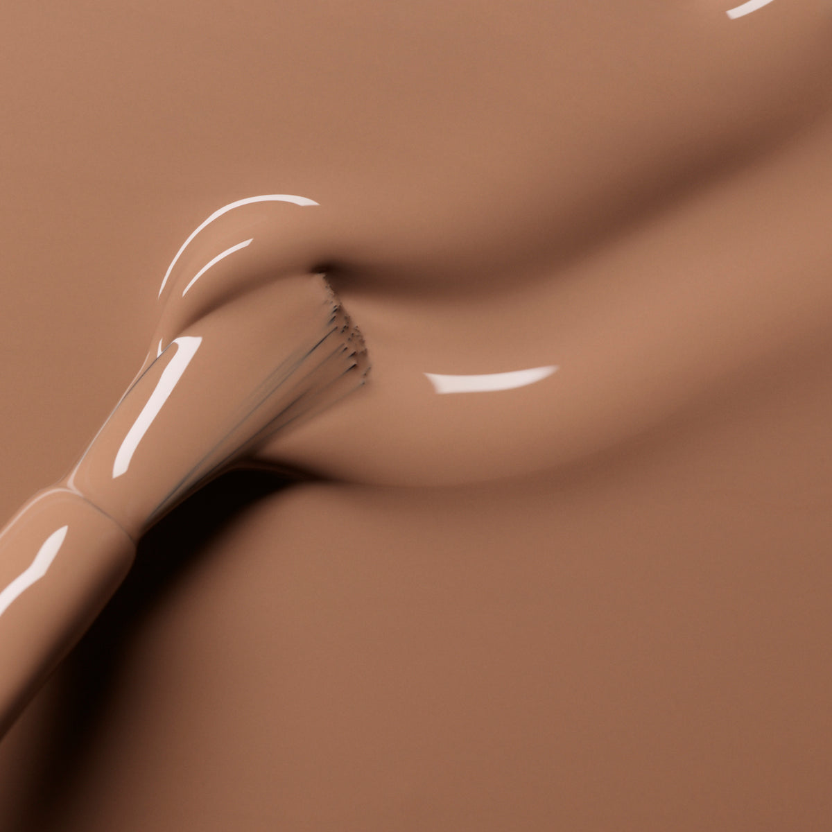 A close-up of a makeup brush spreading beige foundation in sweeping lines, resembling the soft, creamy elegance of Manucurist’s Orme nail polish.