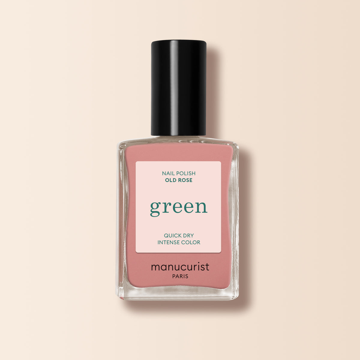 A bottle of Manucurist Old Rose nail polish, an antique powder pink shade, with a pink label featuring green and black text, set against a light beige background.