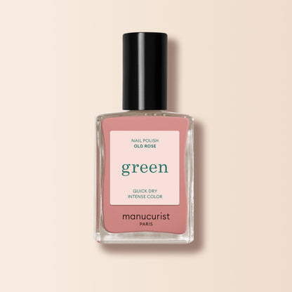 A bottle of Manucurist Old Rose nail polish, an antique powder pink shade, with a pink label featuring green and black text, set against a light beige background.