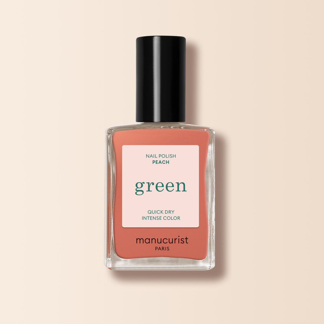 Un flacon de vernis à ongles Manucurist dans la teinte Peach, avec un bouchon noir et une étiquette pêche aux inscriptions blanches et vertes, posé sur un fond beige clair. Idéal pour apporter une touche estivale subtile à vos ongles.