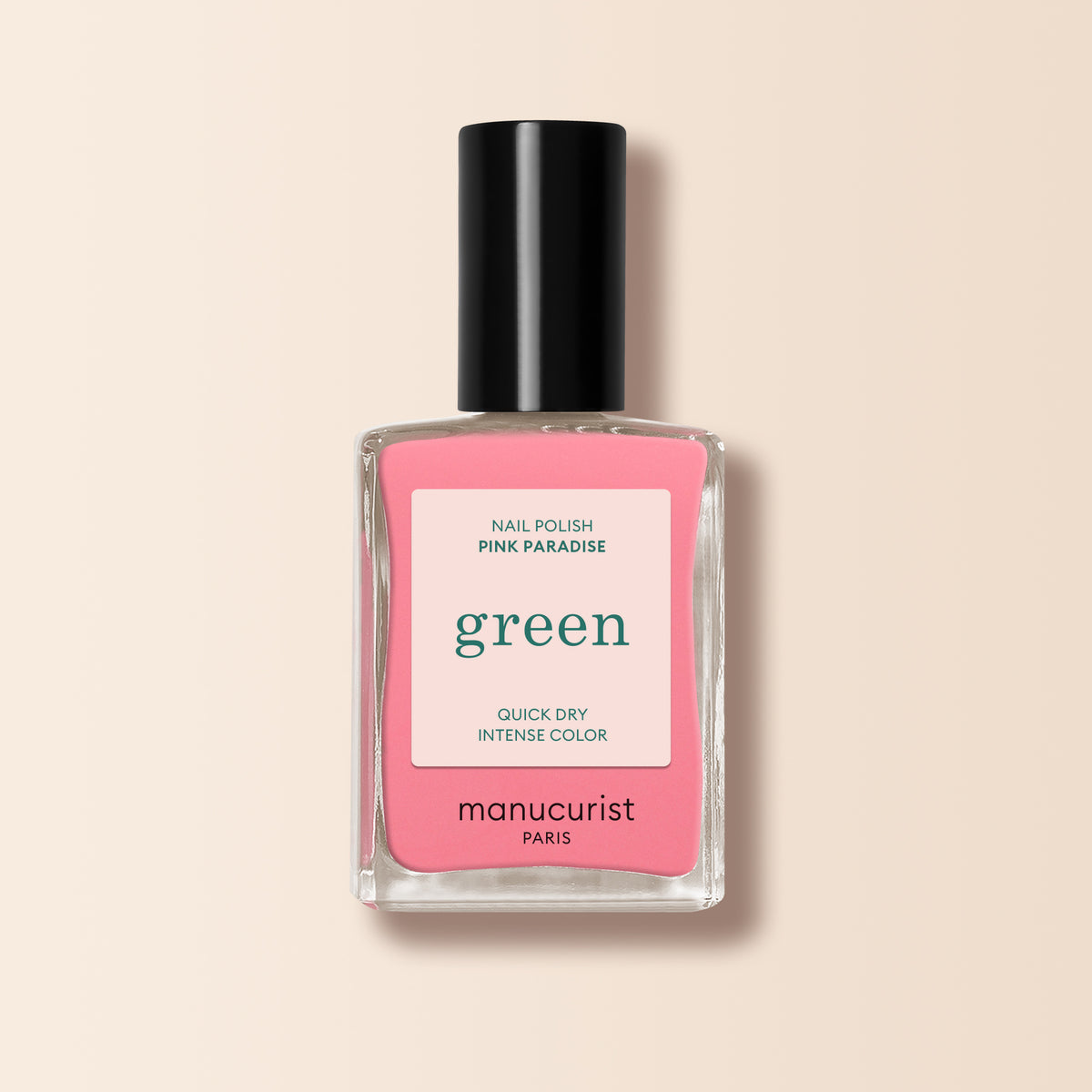 A bottle of Manucurist Pink Paradise nail polish from the Green range, featuring a black cap and pink label, sits on a light beige background.
