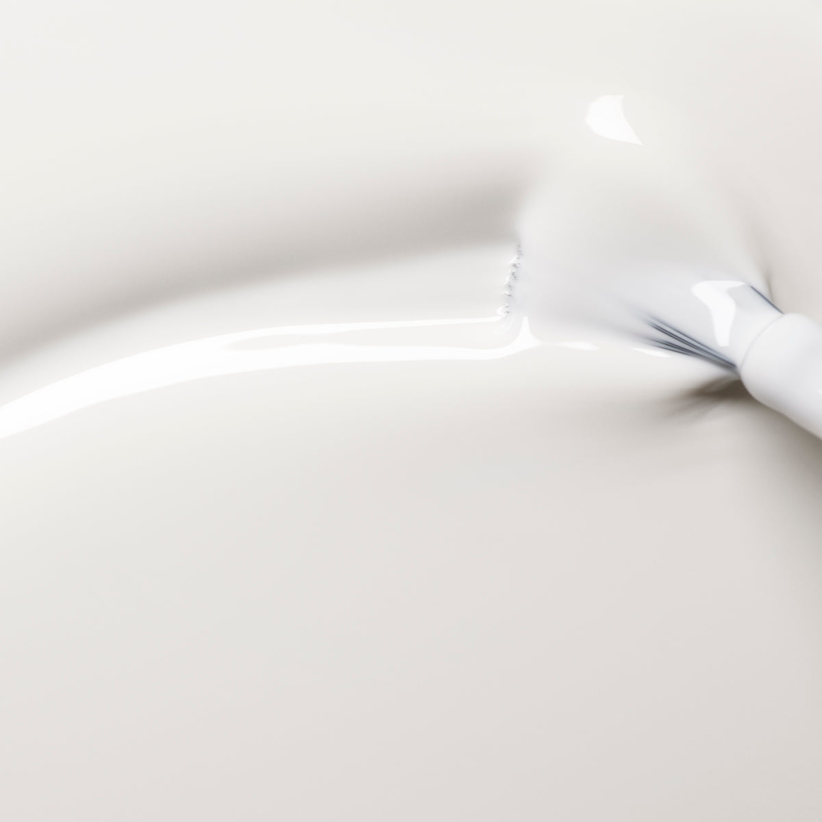 A close-up of Manucurist’s Snow—a pure white, creamy nail polish—being smoothly brushed onto a pale surface, creating glossy and textured strokes.