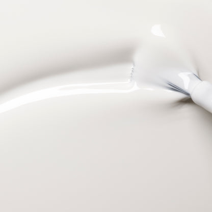 A close-up of Manucurist’s Snow—a pure white, creamy nail polish—being smoothly brushed onto a pale surface, creating glossy and textured strokes.