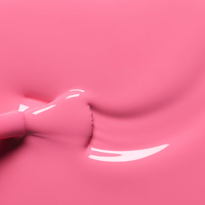 Gros plan sur le vernis à ongles Rose de Manucurist qui s’étale uniformément, révélant des reflets brillants à la surface du liquide, tandis qu’un pinceau est partiellement visible à gauche.