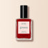 A bottle of Manucurist Red Cherry nail polish with a black cap and "green, quick dry intense color" label is set against a beige background.