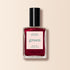 Un flacon en verre transparent de vernis à ongles Manucurist Red Hibiscus avec un bouchon noir et une étiquette indiquant « Quick Dry Intense Color » est présenté, avec le nom du produit sur un fond clair.