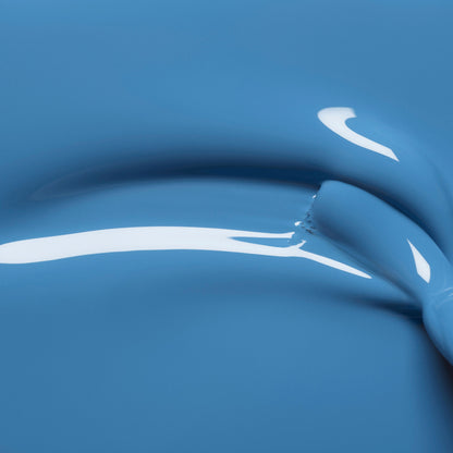 Gros plan sur la teinte Manucurist Saphir brillante et lisse, avec une épaisse traînée incurvée et des reflets lumineux, révélant une texture fluide aux tons précieux.