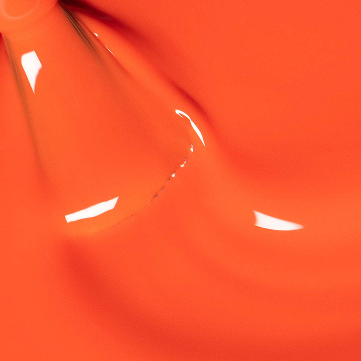 Gros plan sur le vernis à ongles Sunset de Manucurist — une teinte orange vibrante et brillante, au fini lisse et lumineux, avec des reflets de lumière formant un motif abstrait fluide.