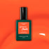 Un flacon de vernis gel Manucurist Sunset, avec une étiquette vert foncé et un bouchon noir, est présenté sur un fond orange vif.