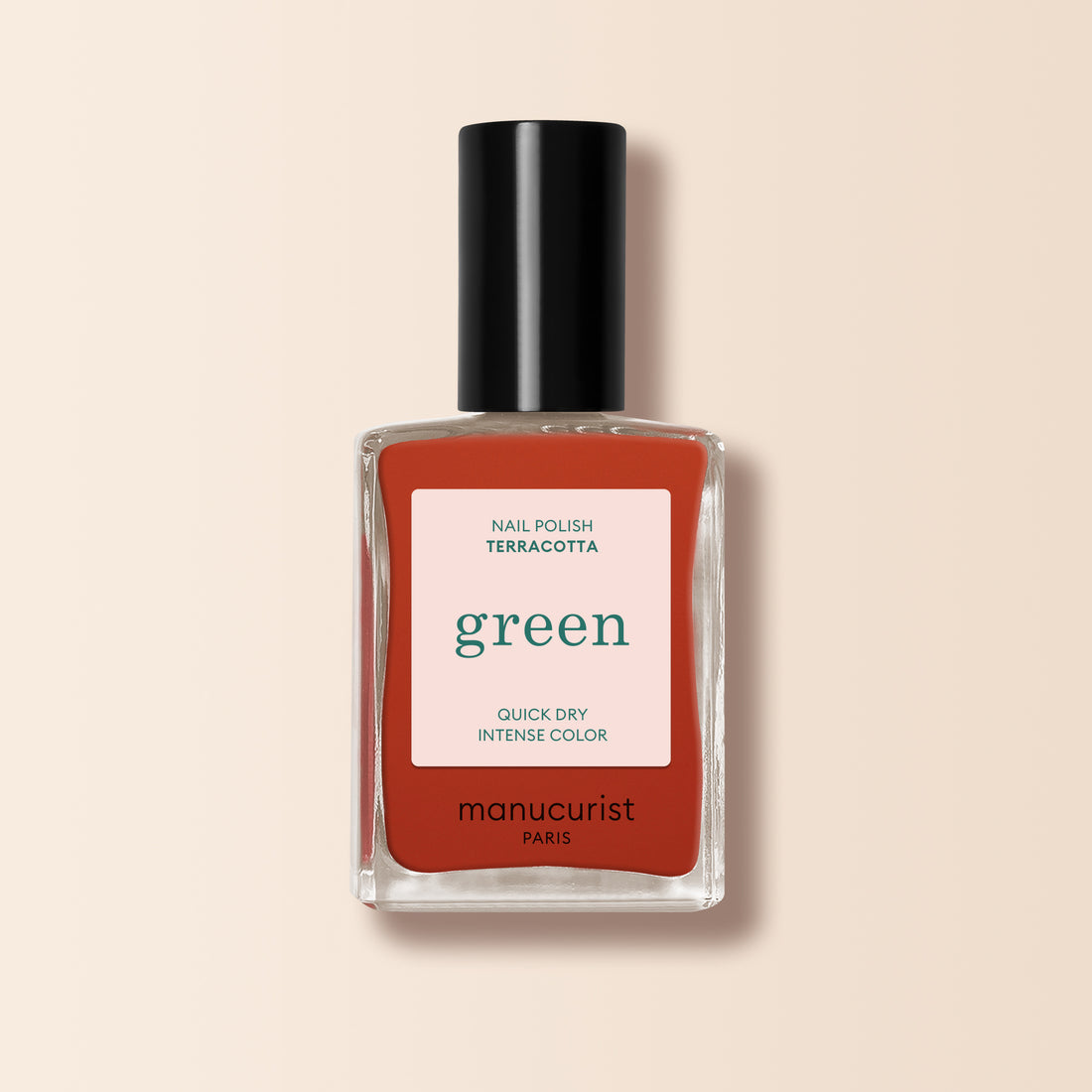 Un flacon de vernis à ongles Manucurist Terracotta dans une teinte rouge terre brûlée, avec un capuchon noir et une étiquette « séchage rapide, couleur intense », présenté sur un fond beige clair.