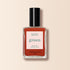 A bottle of Manucurist Terracotta nail polish in a scorched red earth shade, featuring a black cap and quick dry intense color label, displayed against a light beige background.