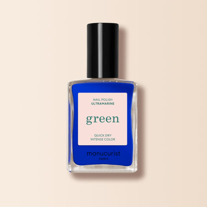 A bottle of Manucurist Ultramarine nail polish with a black cap, labeled "Nail Polish Ultramarine Green" and "Quick Dry Intense Color," from the Green™ range on a beige background.
