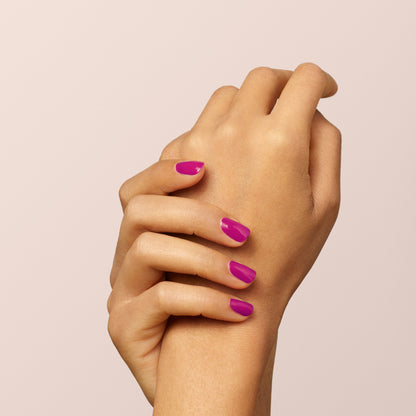 A close-up of two hands with neatly manicured nails painted in bright mauve Armeria nail polish by Manucurist, set against a pale, neutral background.