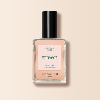 A bottle of Manucurist Beige nail polish with a black cap, labeled “green” and “quick dry intense color,” is shown against a light beige background.