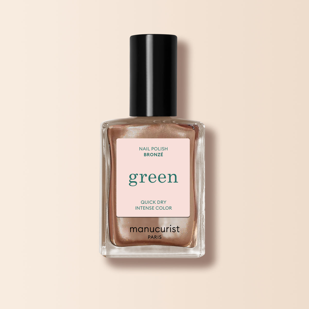 A bottle of Manucurist Bronzé nail polish in a bronze-copper shade with a black cap, set on a light beige background. The label highlights Quick Dry Intense Color.
