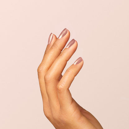 Une main à la peau mate sur fond clair, les doigts délicatement fléchis pour dévoiler des ongles impeccablement manucurés avec le vernis Manucurist Cosmic Rose, un rose irisé.