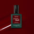 A bottle of Manucurist Dark Pansy gel polish rests on a glossy, deep red background with a matching swipe of velvet red nail color beside it.