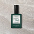 A bottle of Manucurist Diamant gel polish rests on a sparkly, light surface. The dark green bottle with a black cap and white label showcases the shimmering silver nail color.