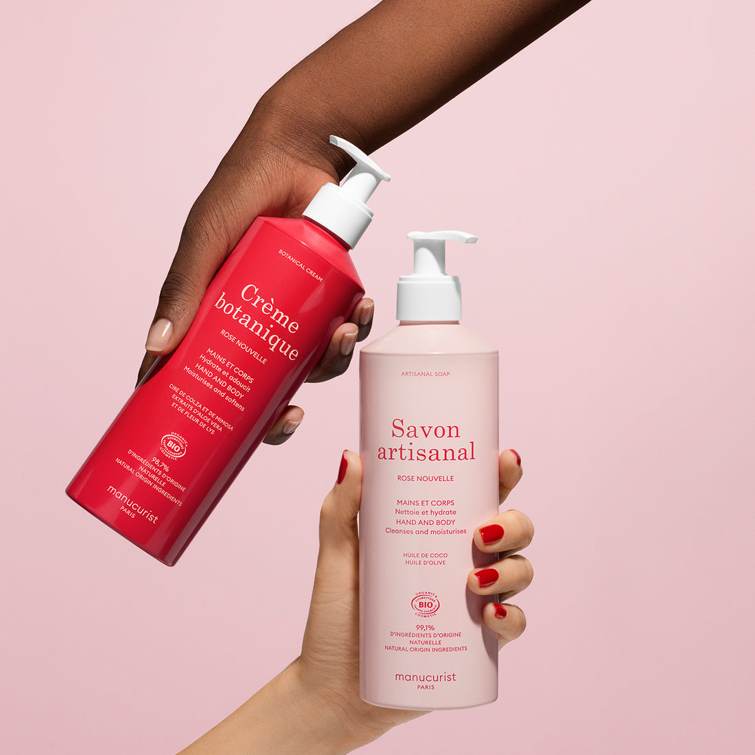 Two hands hold Manucurist’s Rose Botanical Cream  Artisan Soap Duo - Cosmos Organic, featuring a red hand cream and a light pink artisan soap bottle against a pink background.