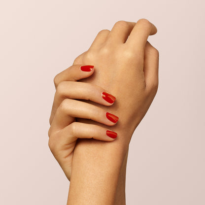 Two hands are shown against a plain, light background. One gently holds the wrist of the other, showcasing neatly manicured nails painted with Manucurist&