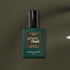 A bottle of Manucurist Khaki gel polish with gray undertones, dark green label, and black cap rests on an olive green surface.