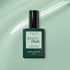 A bottle of Manucurist Mint Green Flash gel polish is displayed on a mint green background with a white swoosh. The dark green bottle features a black cap and a pastel green label.