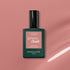 A bottle of Manucurist Old Rose, a beautiful antique pink polish, sits on a pink surface casting a soft shadow. The bottle has a dark green base and black cap.