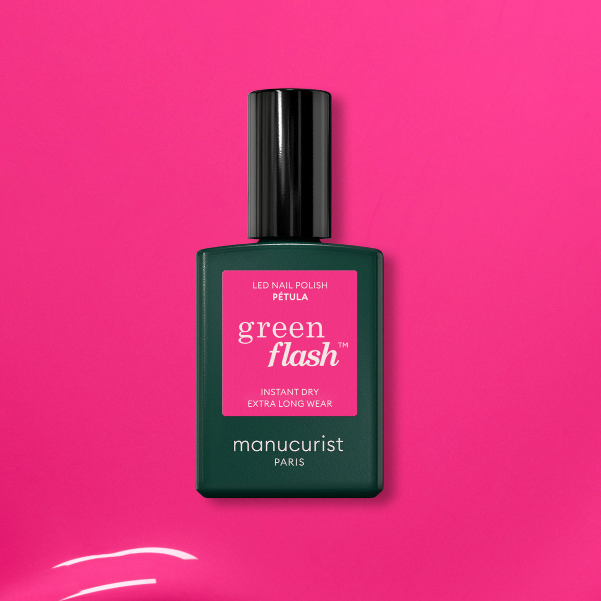 A green bottle of Manucurist’s Pétula pink gel polish rests on a vibrant pink background. This summer shade delivers instant dry, extra long wear, and subtle blue undertones for standout nails.