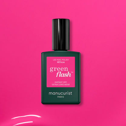 A green bottle of Manucurist’s Pétula pink gel polish rests on a vibrant pink background. This summer shade delivers instant dry, extra long wear, and subtle blue undertones for standout nails.