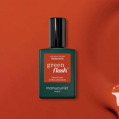 Un flacon de vernis gel Terracotta de Manucurist est présenté sur un fond inspiré de la terre rouge. Le flacon rectangulaire présente un corps vert foncé et un élégant bouchon noir, mettant en valeur la riche teinte Terracotta.